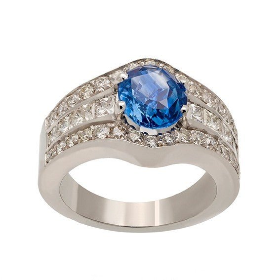 Bague en or blanc 18 carats surmountée d’un saphir ovale 1,76 ct serti 4 griffes, tri-rangs de diamants princesses et ronds, vue de face