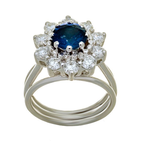 Bague entourage en or blanc 18 carats, saphir rond bleu intense environ 1,55 carat en serti griffes, halo de 10 diamants ronds brillants serti griffes, corps triple anneau fil poli, vue de face