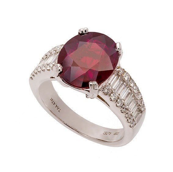 Bague en or blanc 18 carats, rubis ovale rouge intense environ 3,50 carats en serti 4 griffes doubles, épaulements composés d’un rang central de diamants baguettes flanqué de deux rangs de diamants ronds serti grain, vue de côté