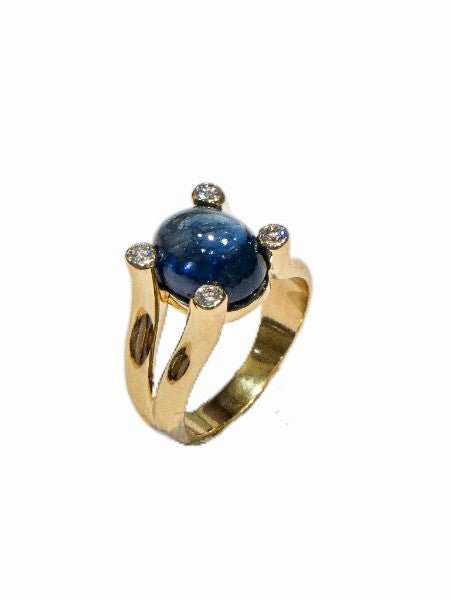 Bague en or jaune 18 carats, saphir ovale cabochon bleu nuit environ 5 carats en serti clos rail, 4 diamants ronds brillants serti lunette aux quatre angles du motif central sur corps fendu anatomique, vue de côté