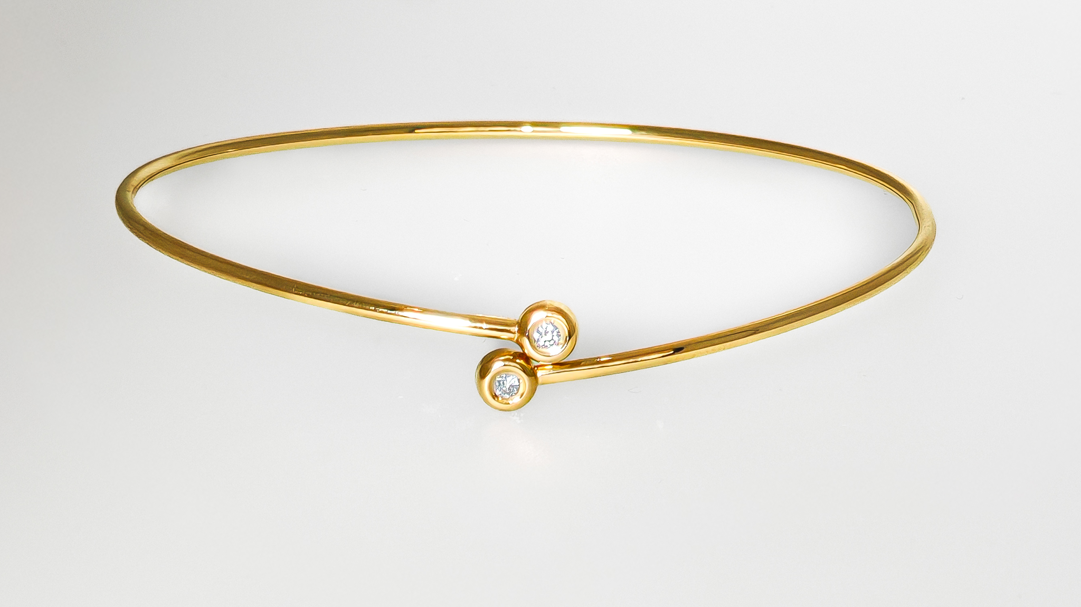 Bracelet jonc en or jaune 18 carats serti de deux diamants sur un fond blanc commercial