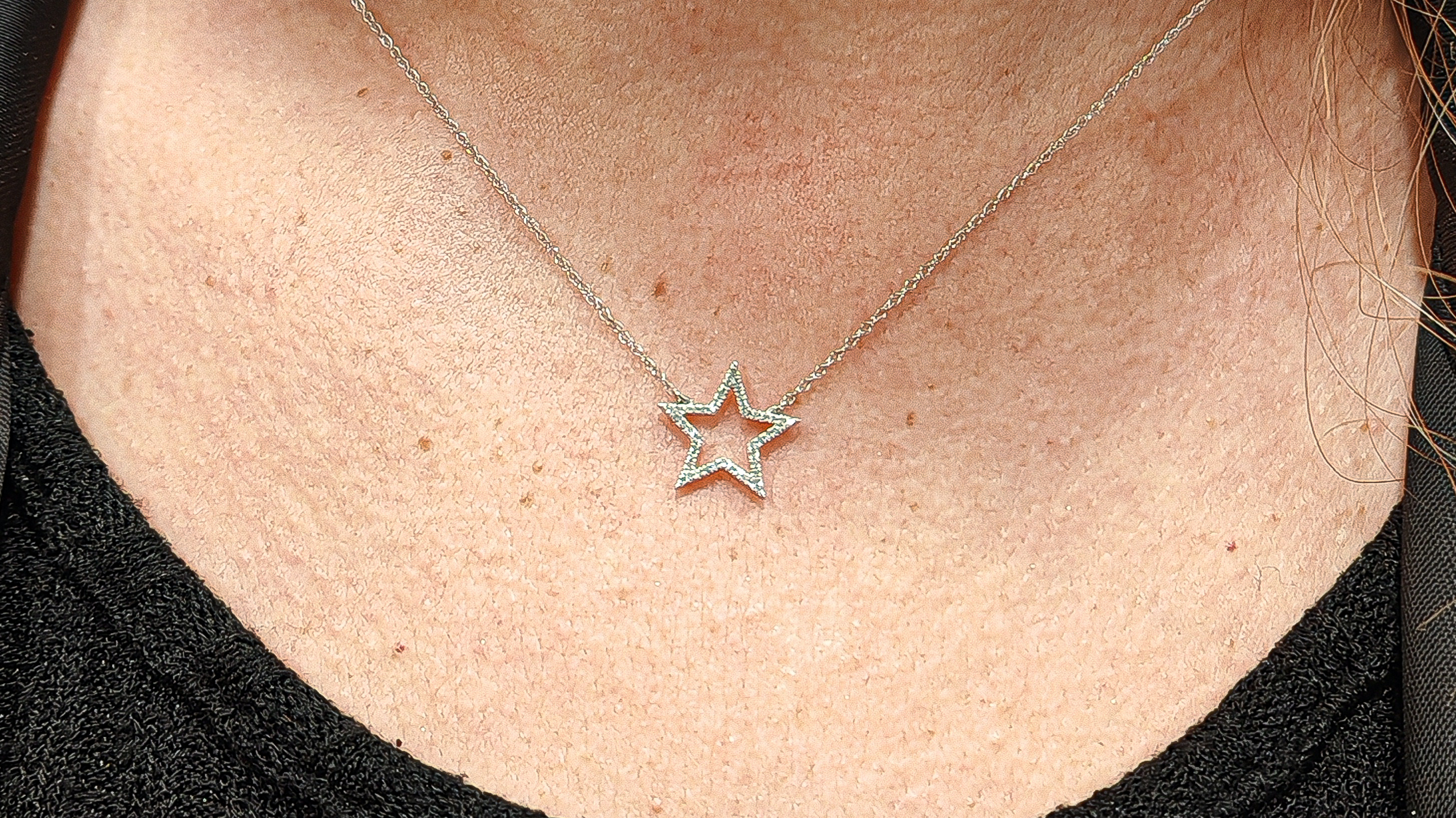 Collier étoile en or 18k serti de diamant porté sur le cou d'une femme.