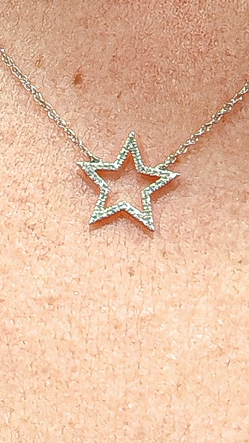 Collier étoile en or 18k qu'une personne porte.